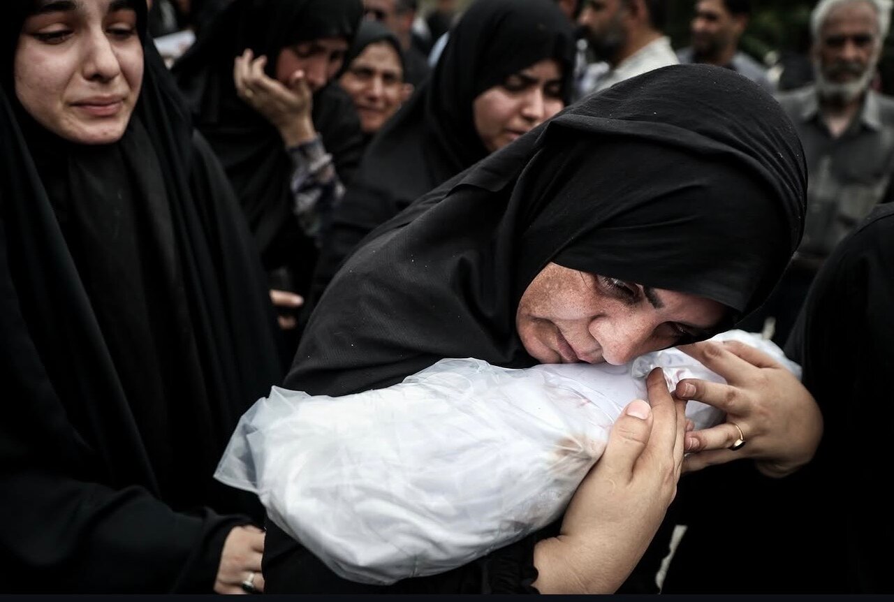مادر مینابی که تکه های بدن فرزندشان در آغوش گرفته است تا به خاک بسپارد
